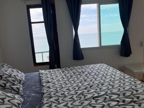 A bedroom with a bed, a window with curtains, and a view of the sea. - Ban Na White Sand Beach (Ko Chang)
