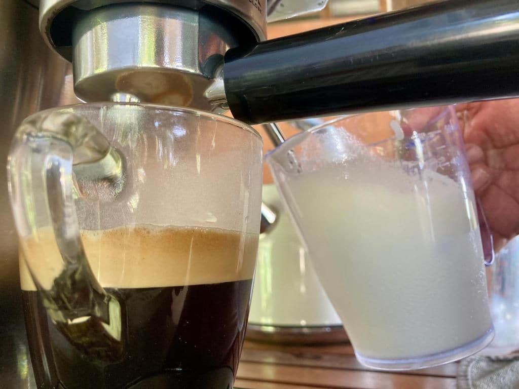 Une machine à café verse du café dans une tasse en verre.