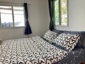 A bedroom with a bed, two windows, and curtains. - Ban Na White Sand Beach (Ko Chang)