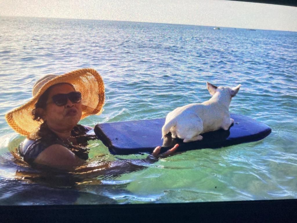 A person in a swimsuit with a straw hat on a floating platform in the water.