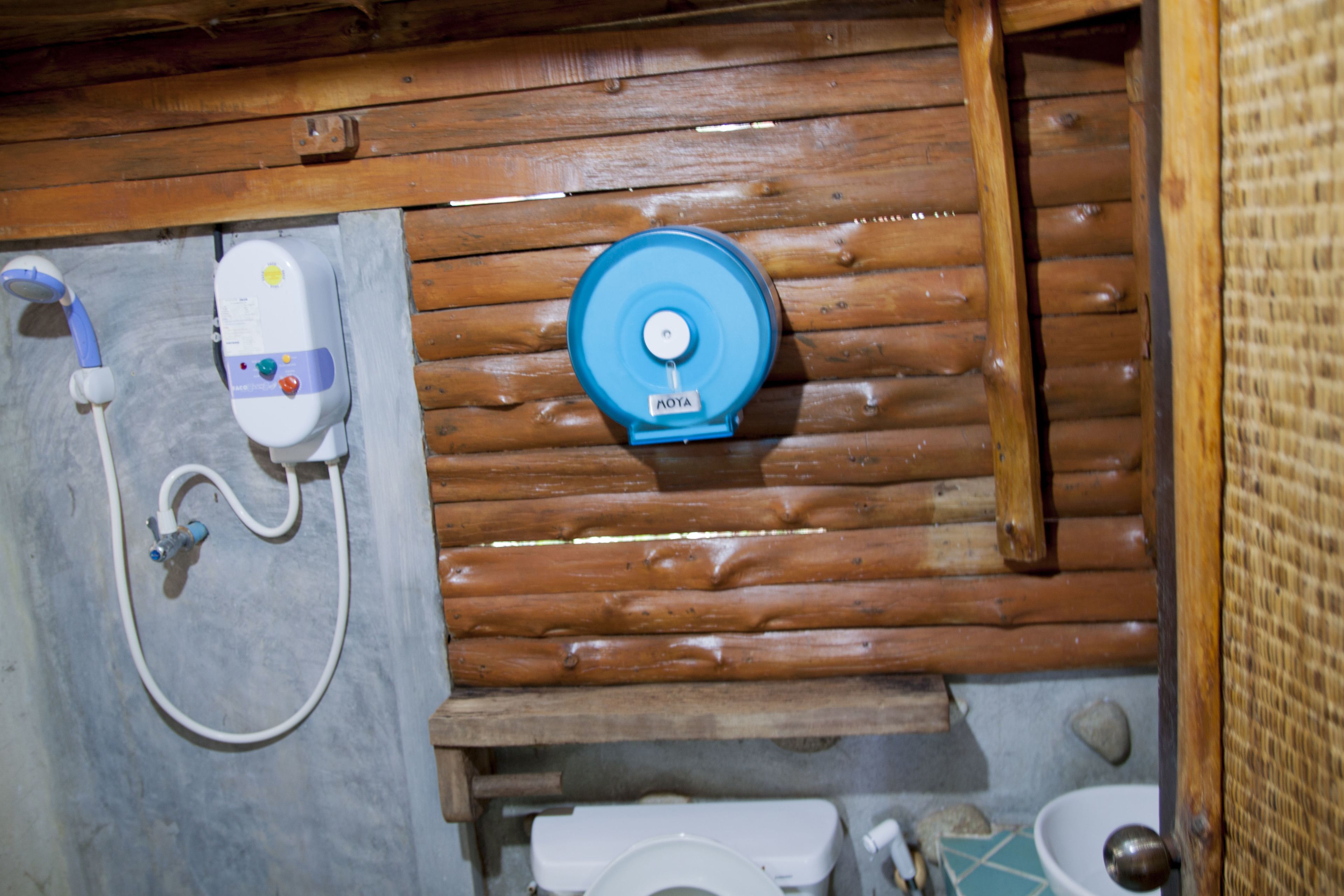 Baño de cabaña de madera con ducha, inodoro y lavamanos.