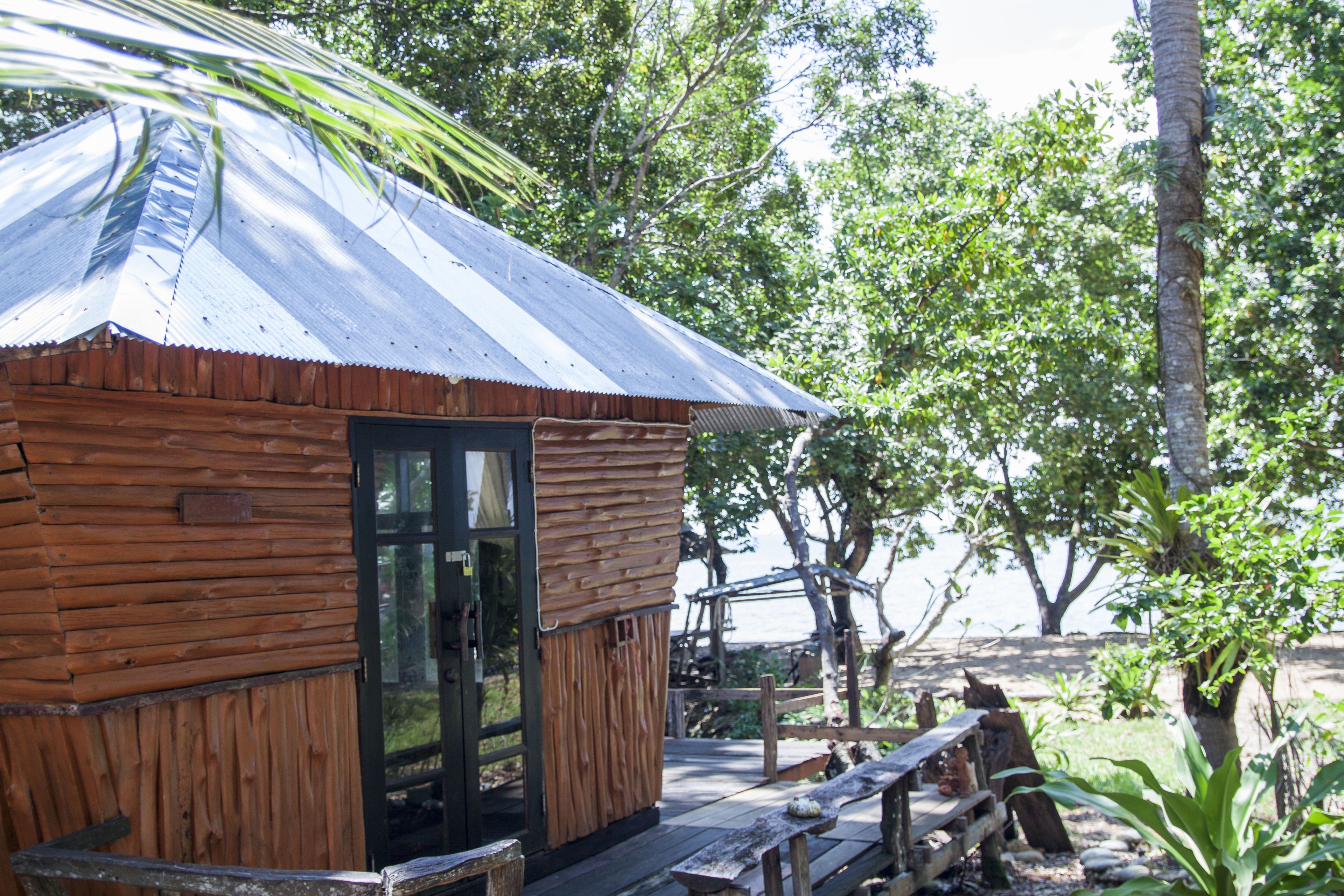 A rustic wooden cabin with a metal roof, a wooden door, and a bench outside.