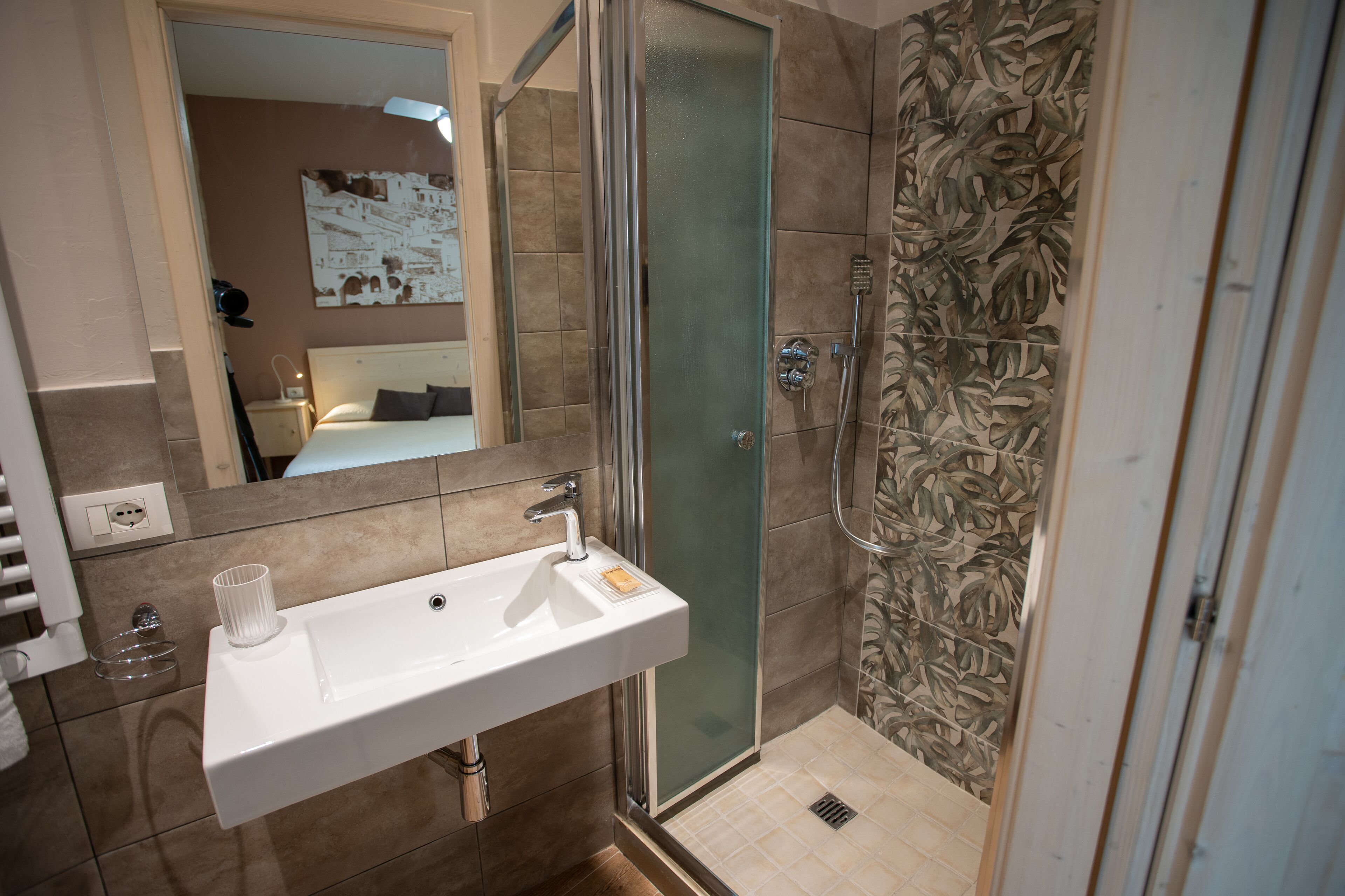 A bathroom with a glass-enclosed shower, a white sink, and a mirror.