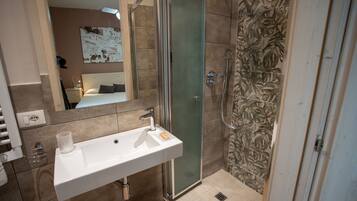 A bathroom with a glass-enclosed shower, a white sink, and a mirror.