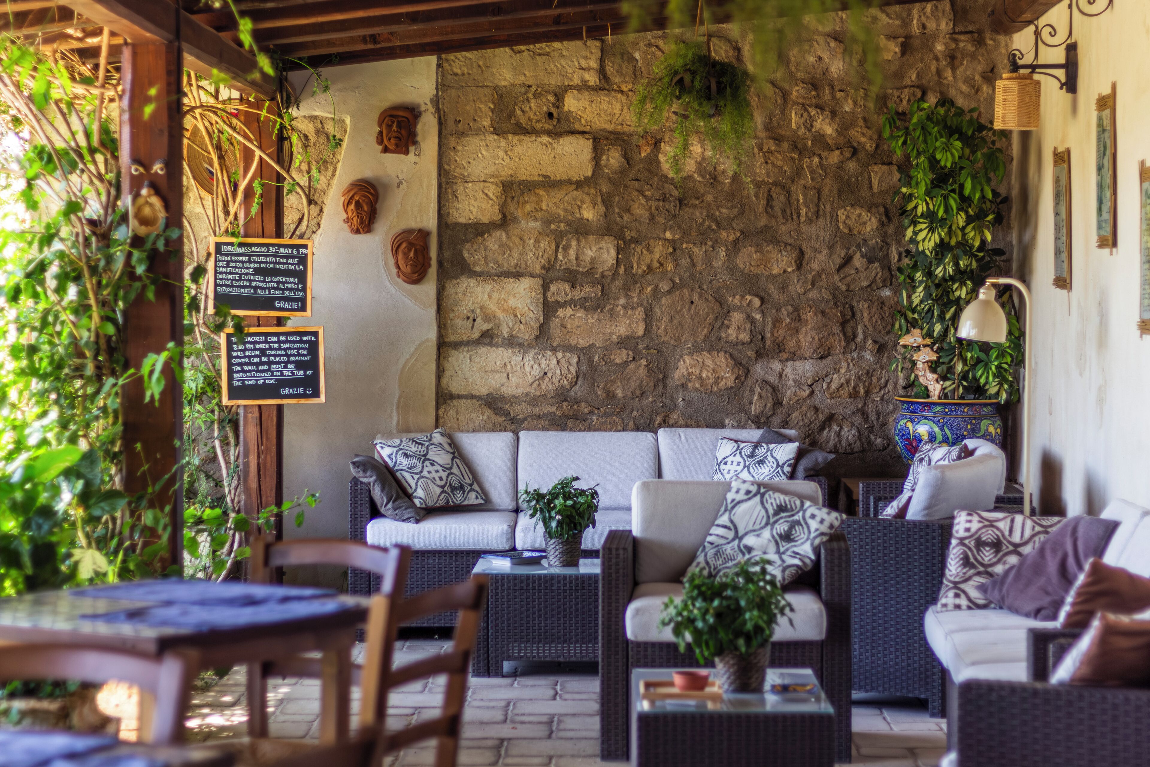 An outdoor seating area with wicker furniture, stone walls, and greenery.