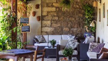 An outdoor seating area with wicker furniture, stone walls, and greenery.