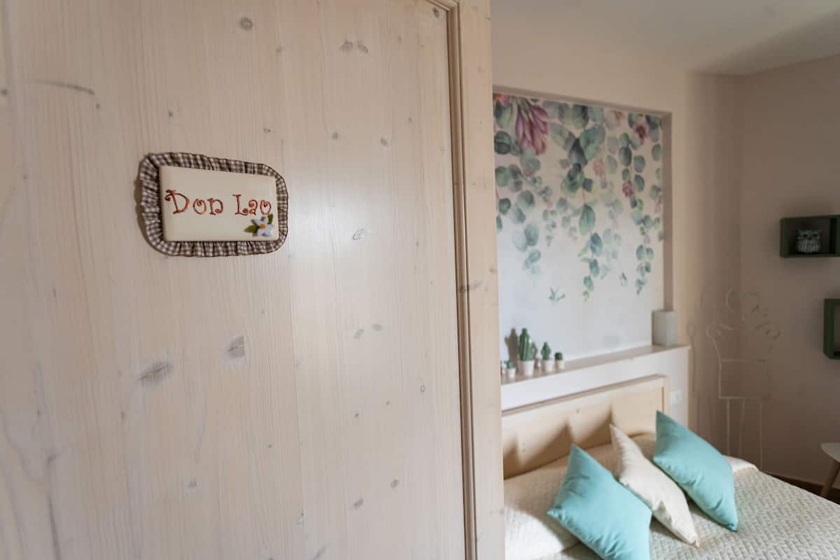 Ein Schlafzimmer mit Bett, Kissen, einem Nachttisch, einem an der Wand montierten Regal und einem dekorativen Schild.