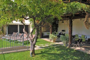 Un patio con un camino de piedra, mobiliario exterior y una pérgola.