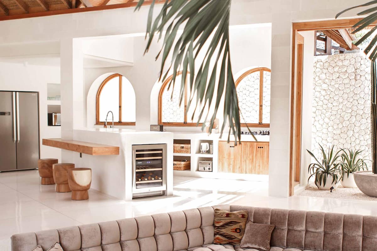 A spacious living area with a large sectional sofa, wooden coffee tables, and a herringbone floor pattern.