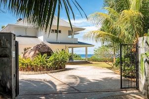 Una casa moderna con un porche cubierto, una roca grande y vista al océano.