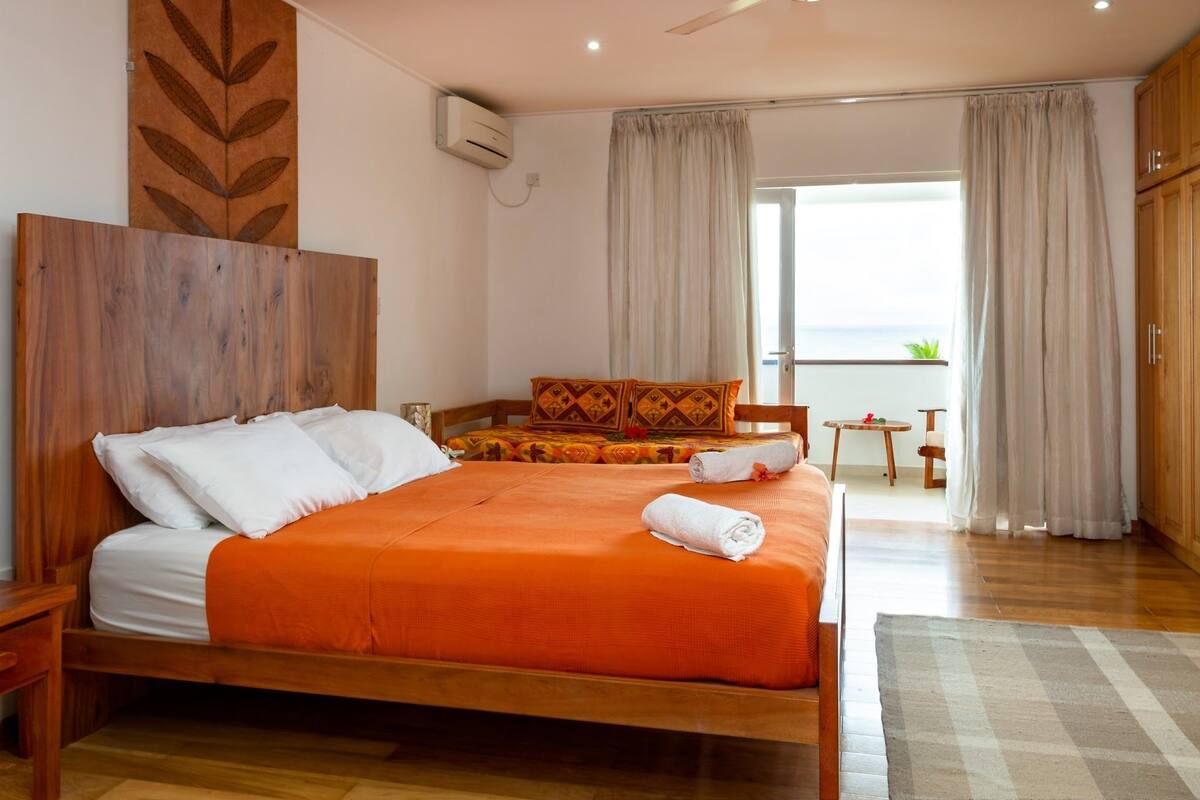 A bedroom with a wooden bed, a small table, and a view of the outdoors.