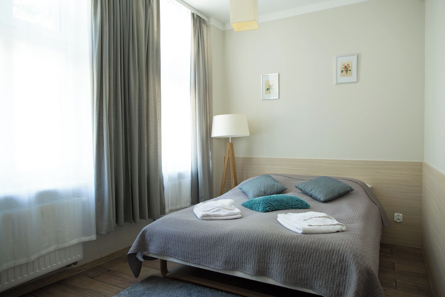 Una habitación de hotel con una cama, una lámpara y dos cuadros en la pared.