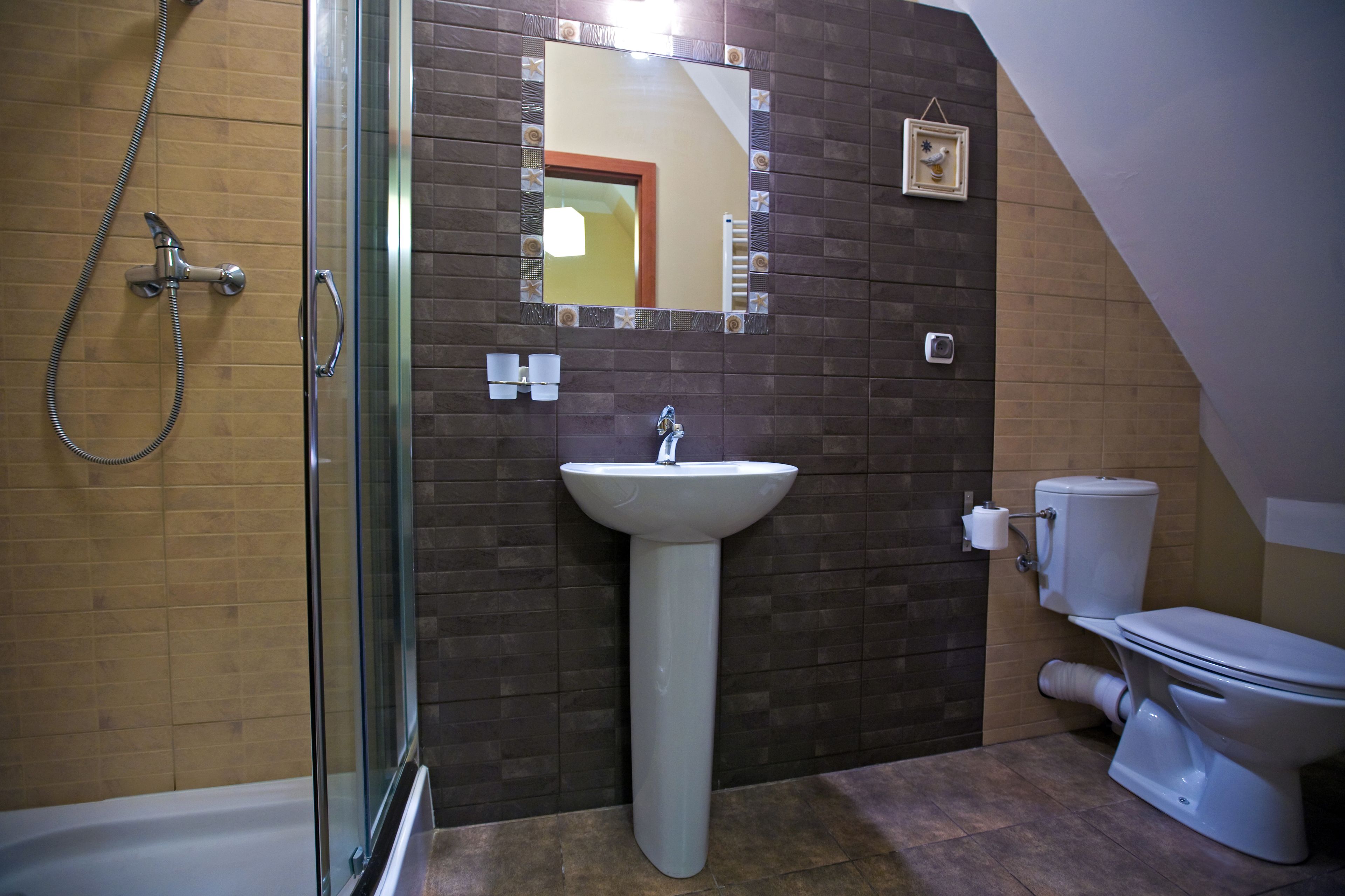Une salle de bain avec une douche à parois de verre, un lavabo sur colonne et des toilettes.