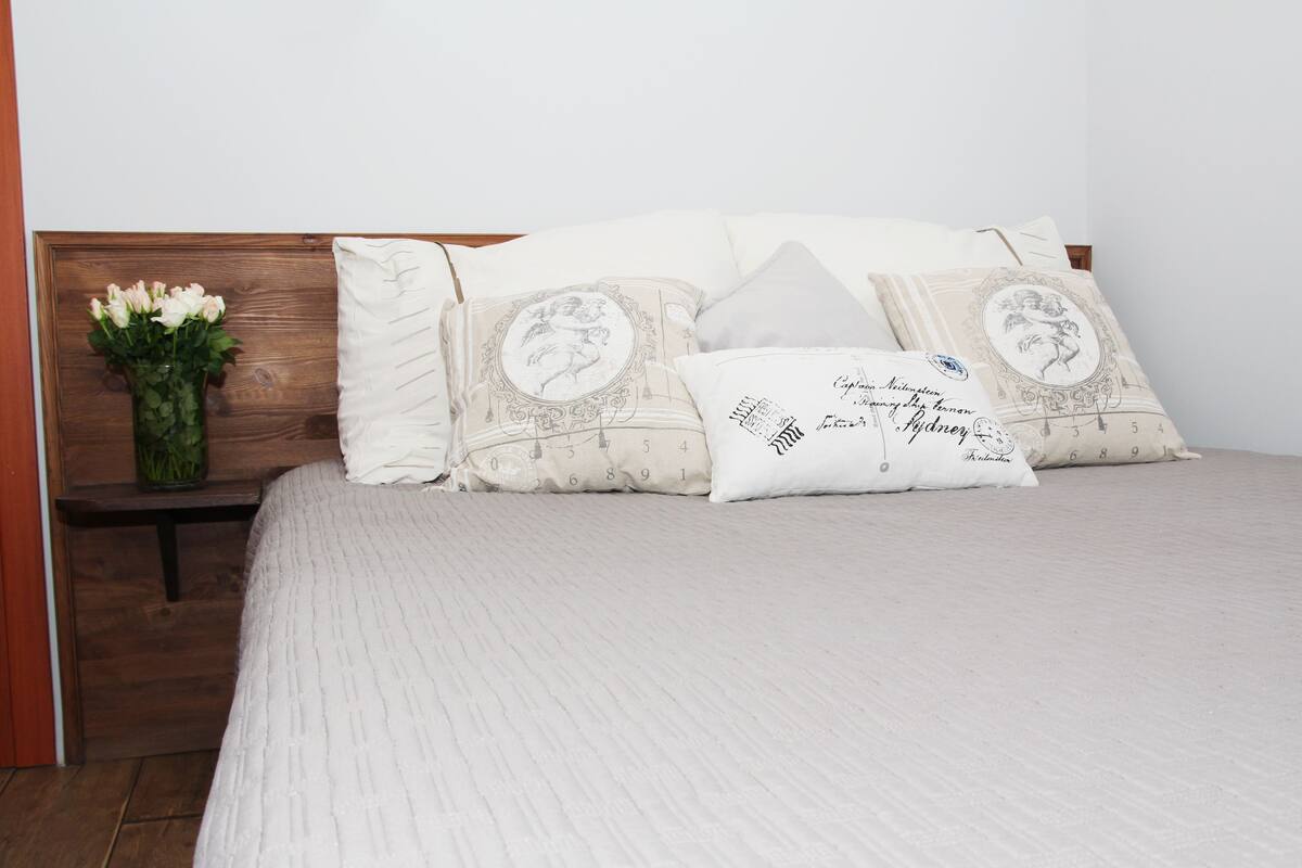 A neatly made bed with a white bedspread and multiple decorative pillows, each with a unique design.