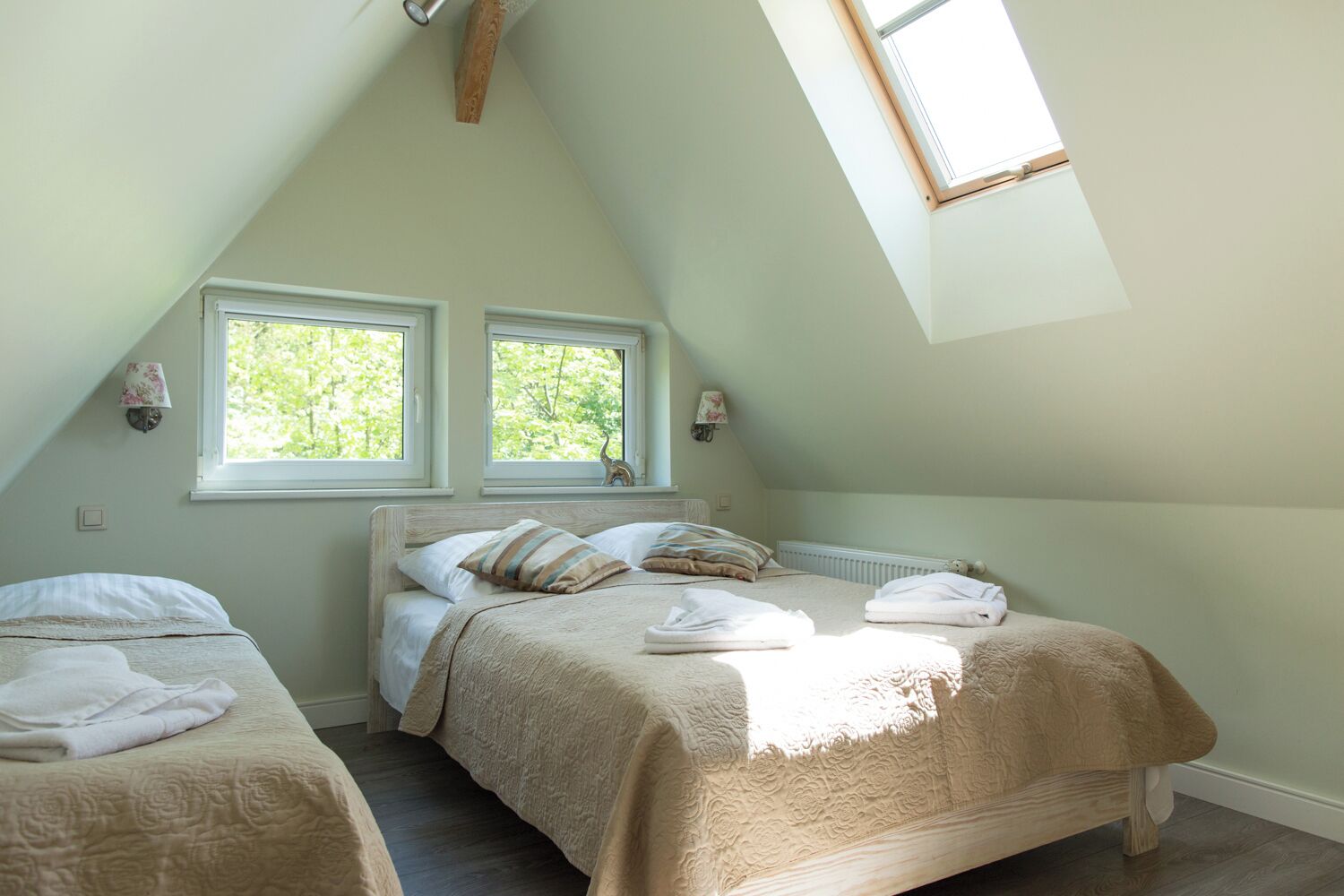 Un dormitorio con dos camas, techo inclinado y dos ventanas.