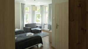 A room with two beds, a sofa, and a window with curtains. - Villa Solis (Swinoujscie)