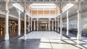 Un vaste atrium agrémenté de colonnes blanches richement décorées, d’un sol à motifs et d’un espace central ouvert.