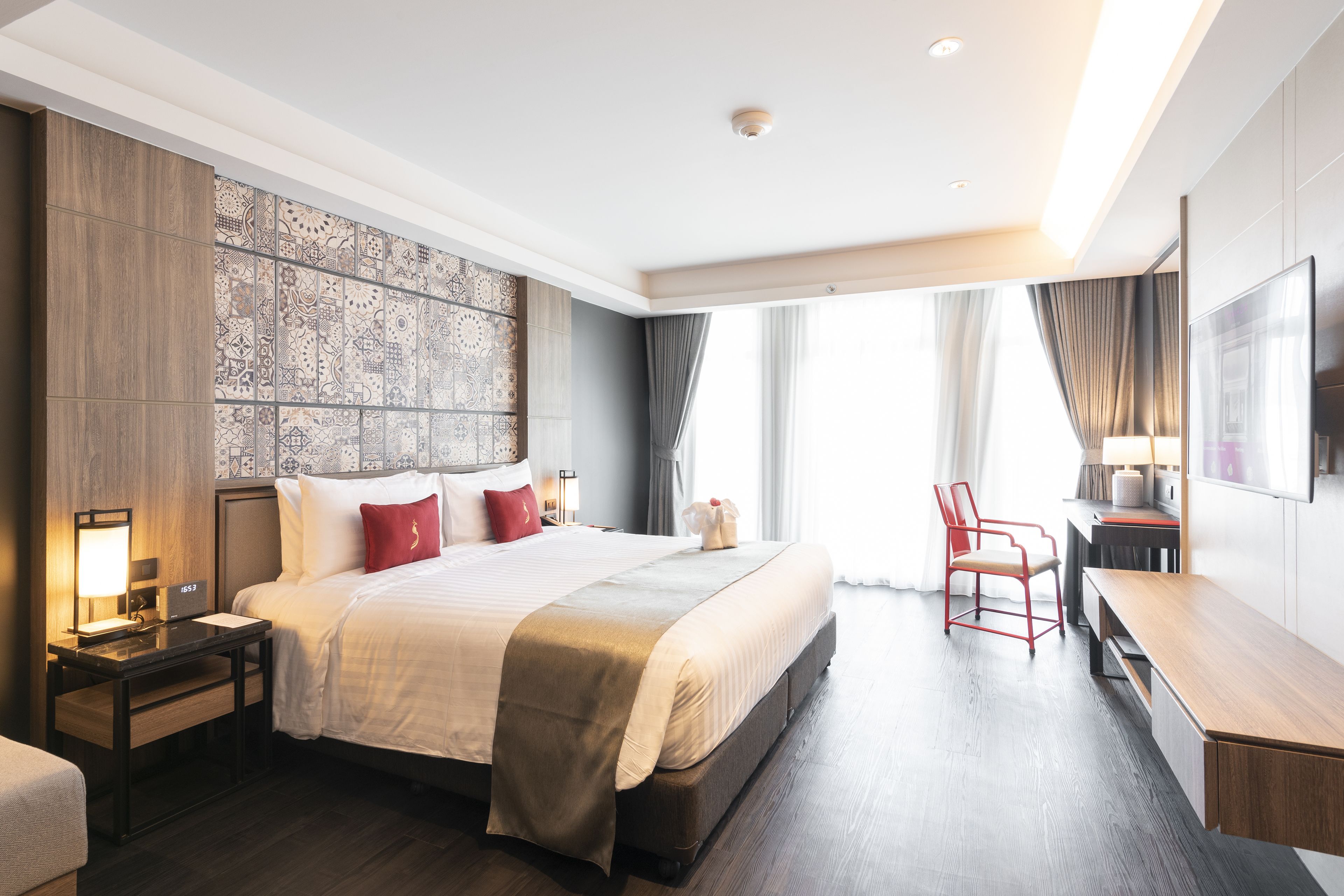 A modern hotel room with a large bed, a desk, and a chair.