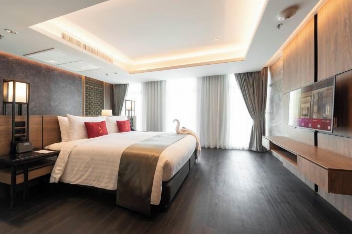 Ein modernes Hotelzimmer mit einem großen Bett, einem Flachbildfernseher und einem Schreibtisch.