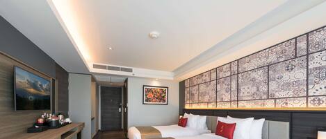 A modern hotel room with two beds, a desk, and a large decorative wall.