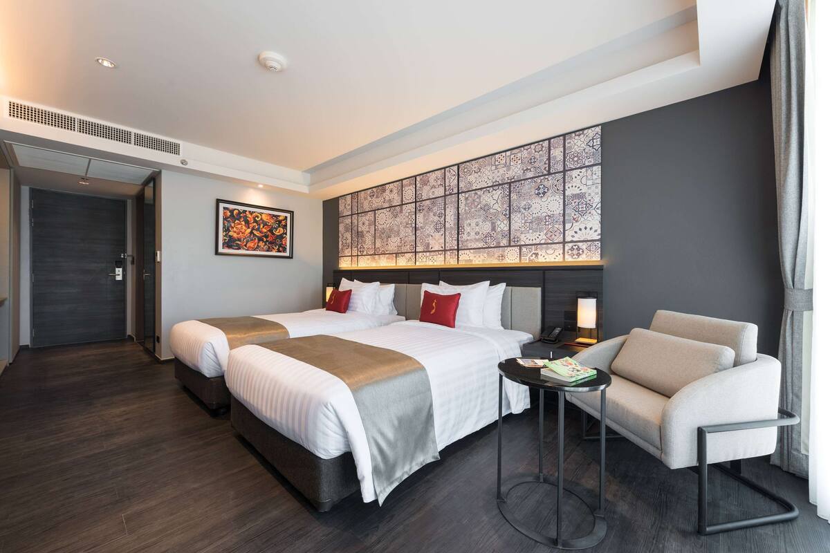 A hotel room with two beds, a sofa, a small table, and a decorative wall panel.
