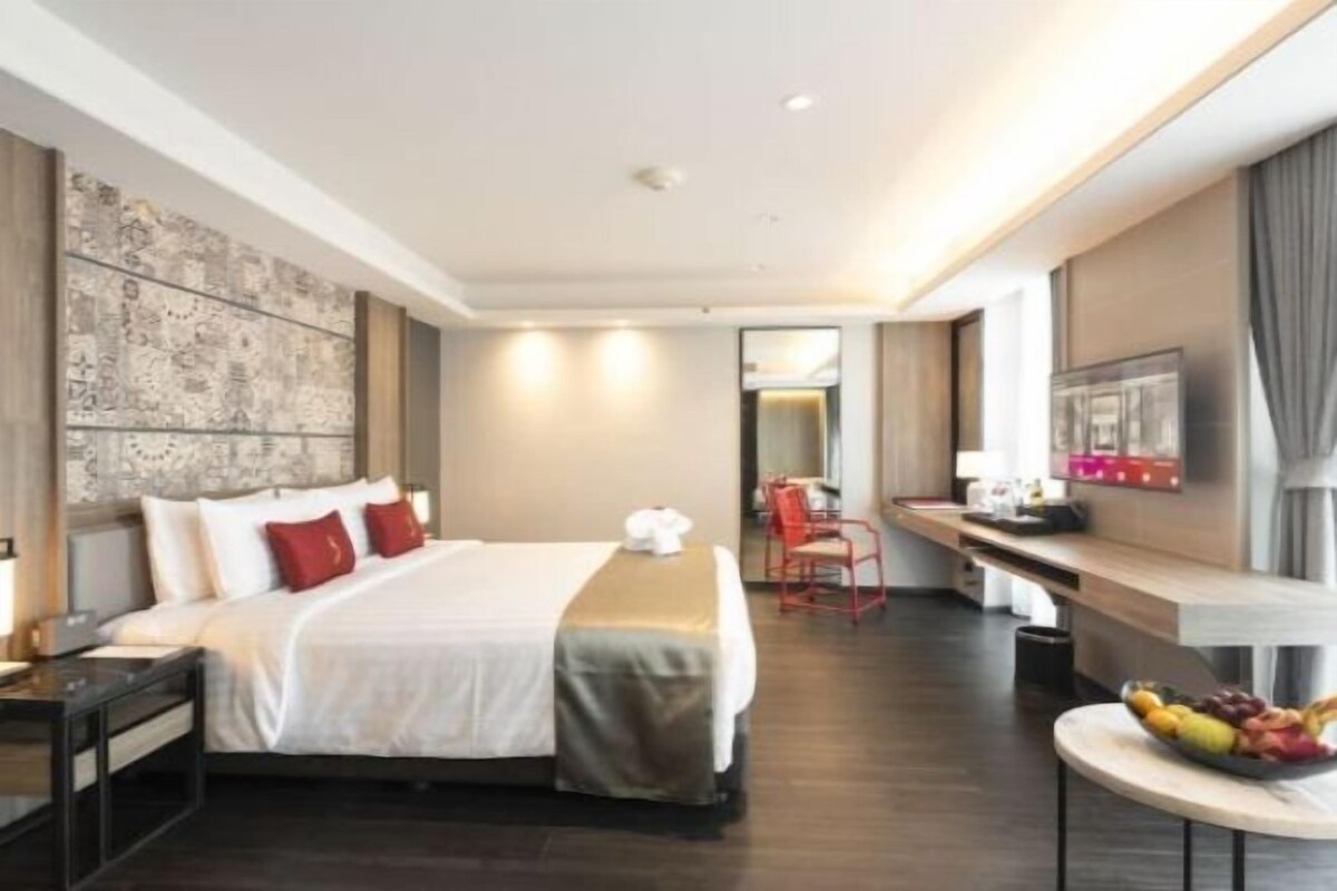 Ein Hotelzimmer mit Bett, Schreibtisch, Stuhl und einem kleinen Tisch mit Obst.