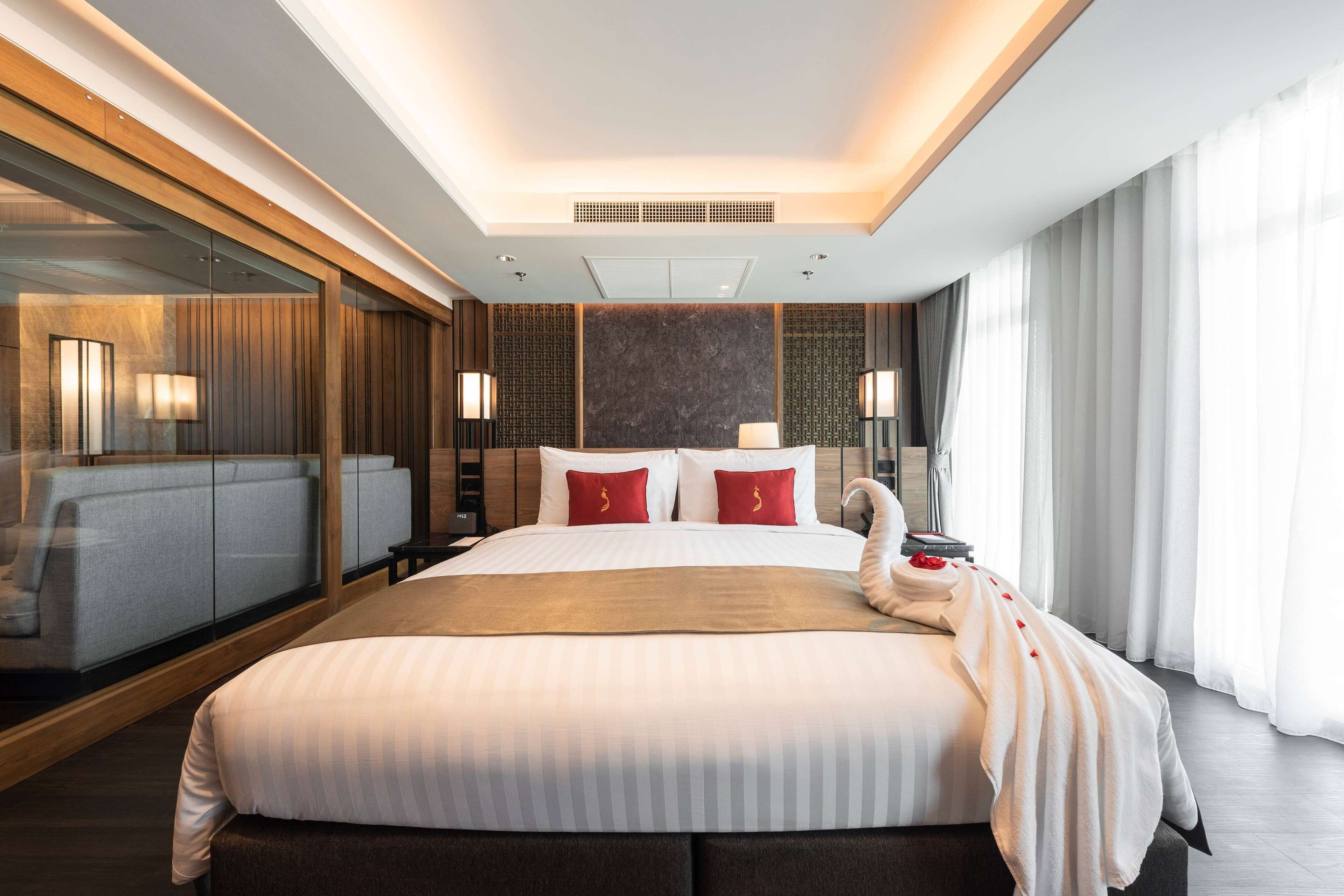 Habitación de hotel moderna con una cama grande, un separador de vidrio y vistas a la ciudad.