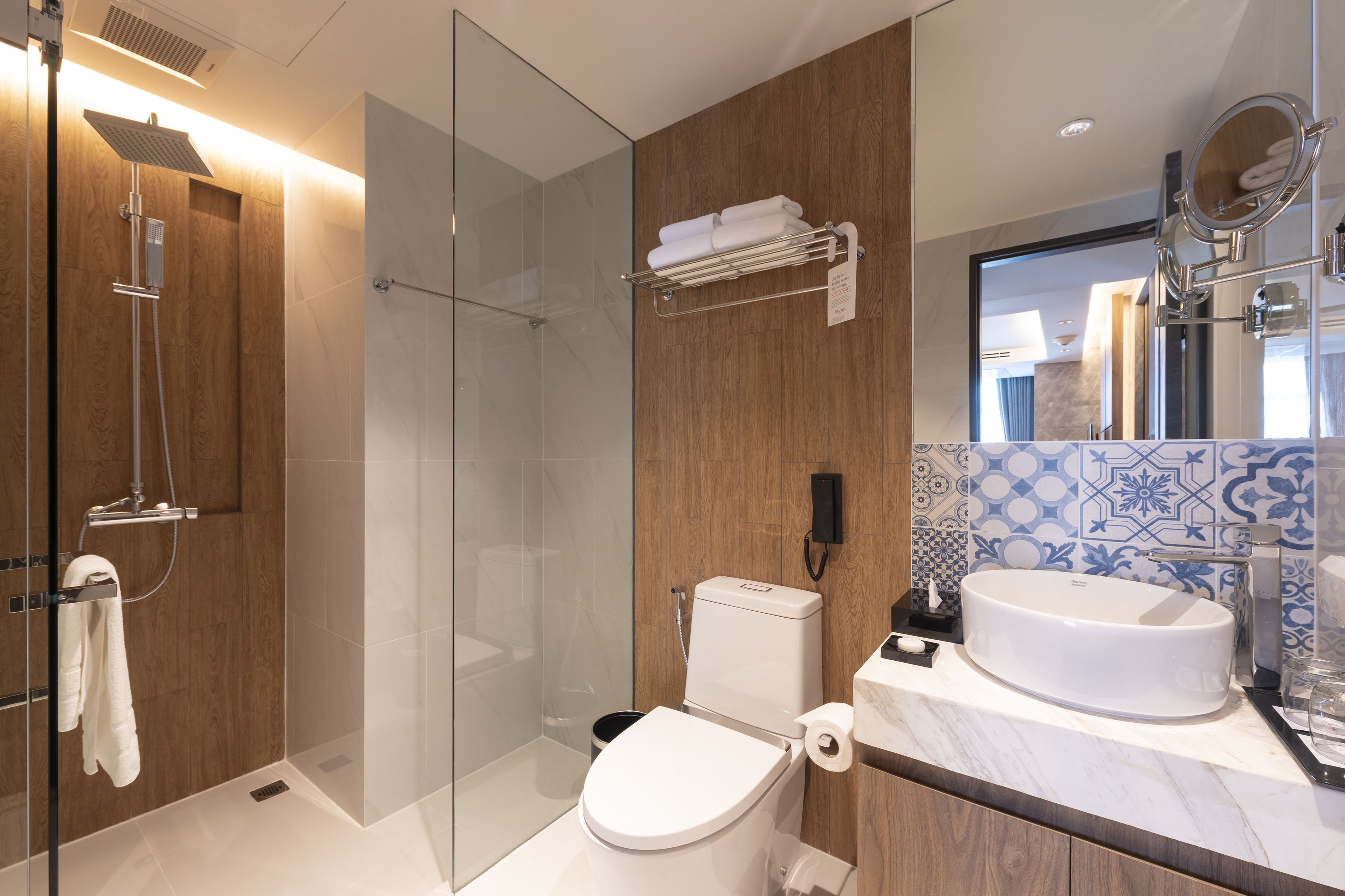 Un bagno moderno con doccia vetro, un water e un lavandino con specchio.