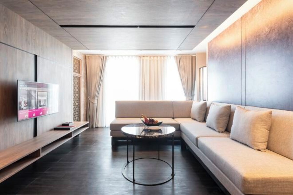 A modern living room with a sofa, a coffee table, and a flat-screen TV mounted on the wall.
