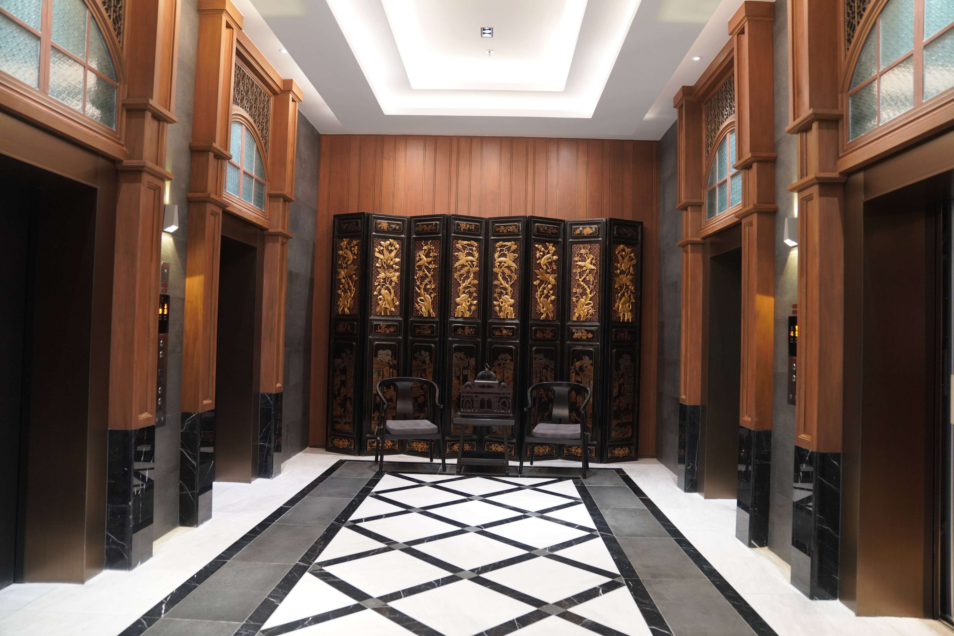 Un hall d’entrée doté d’un sol à motifs géométriques, de lambris en bois et d’un paravent décoratif aux motifs complexes.