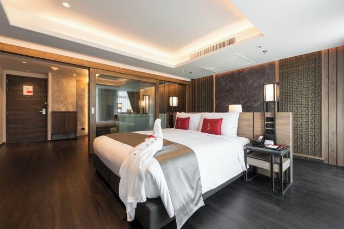 A modern hotel room with a large bed, bedside tables, and a walk-in closet.