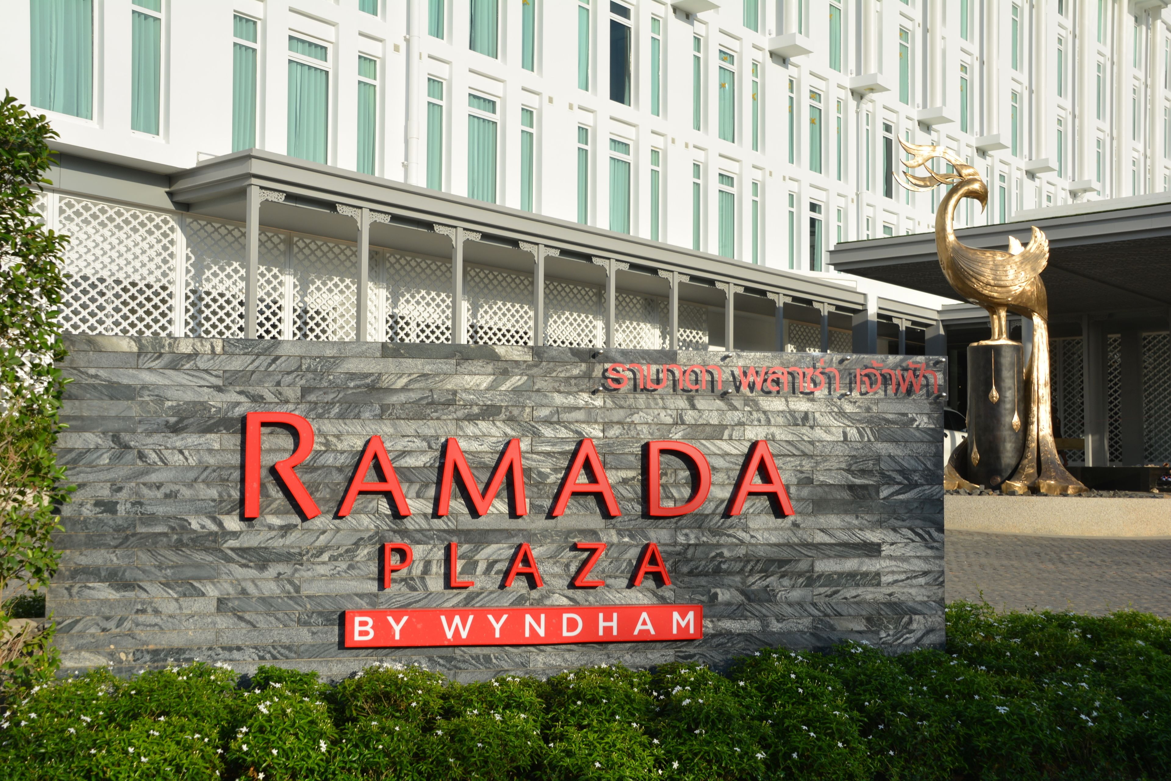 Ein Schild für Ramada Plaza by Wyndham, mit modernem Design, einer Stein-Fassade und dekorativen Elementen.