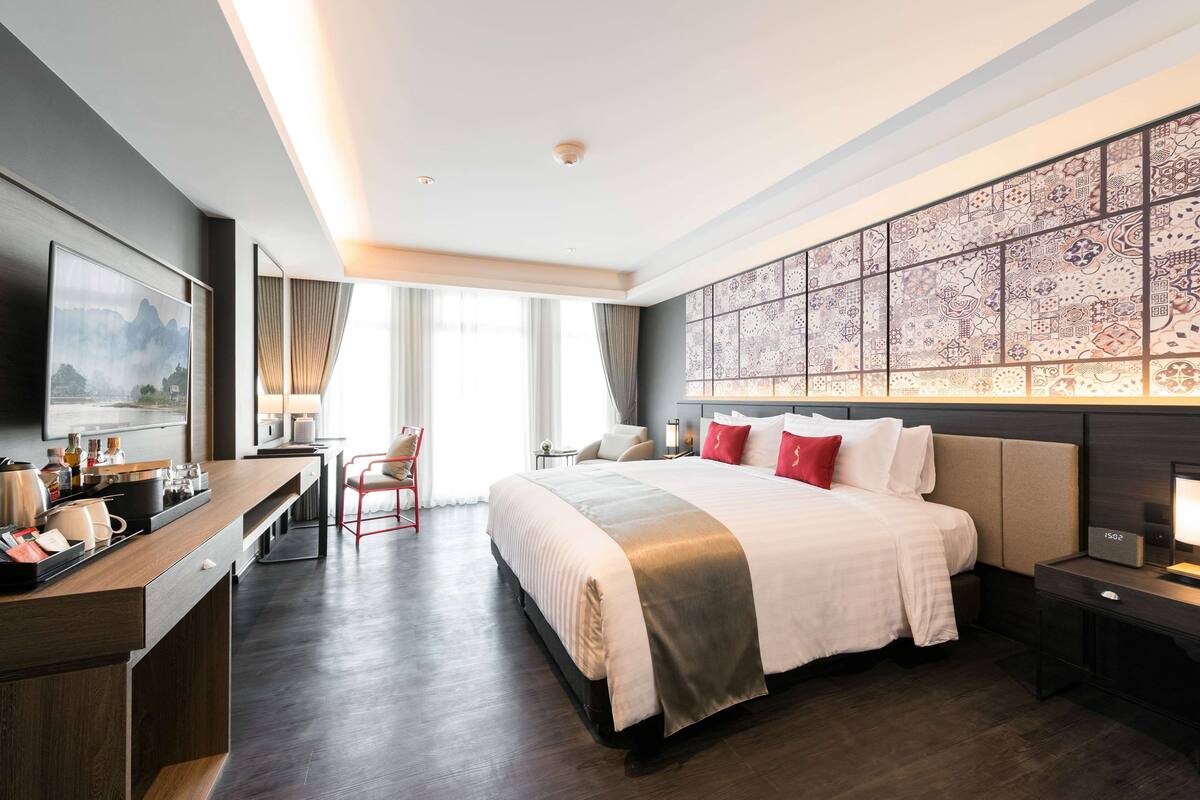 A modern hotel room with a large bed, a desk, and a TV.