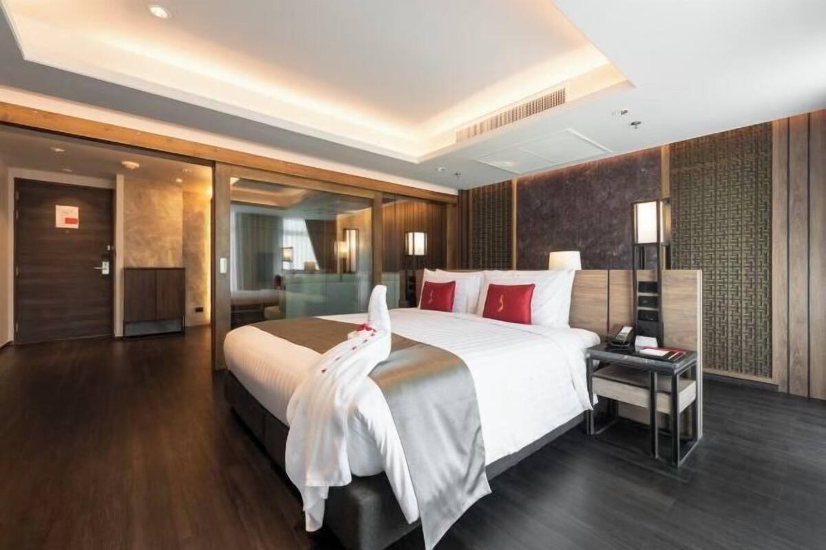 A modern hotel room with a large bed, bedside table, and a mirror.