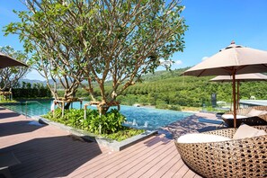 Un espace aménagé au bord de la piscine, avec une terrasse en bois, des chaises longues et un parasol.