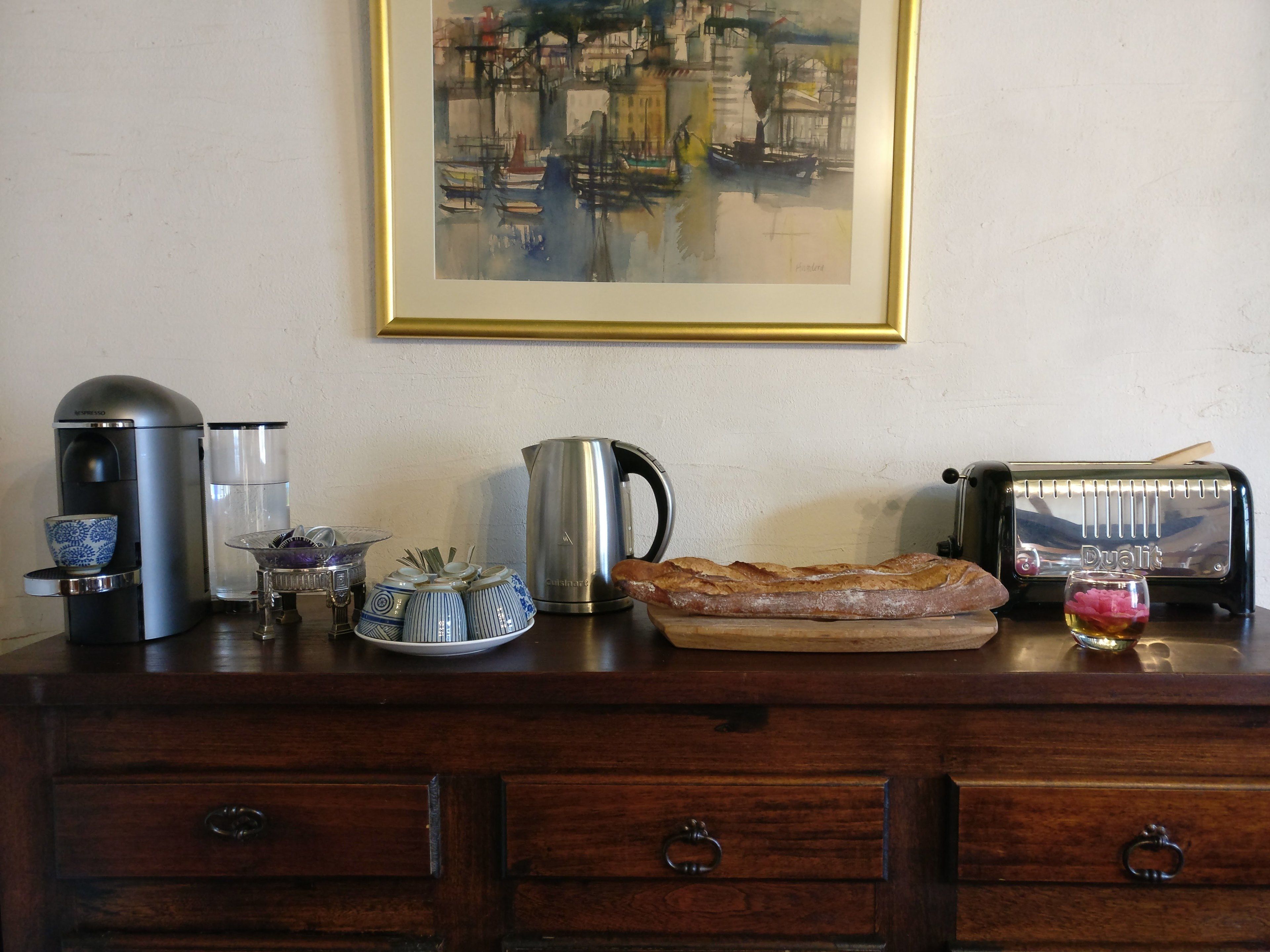 Een aanrecht met een koffiezetapparaat, waterkoker, broodrooster en een brood.