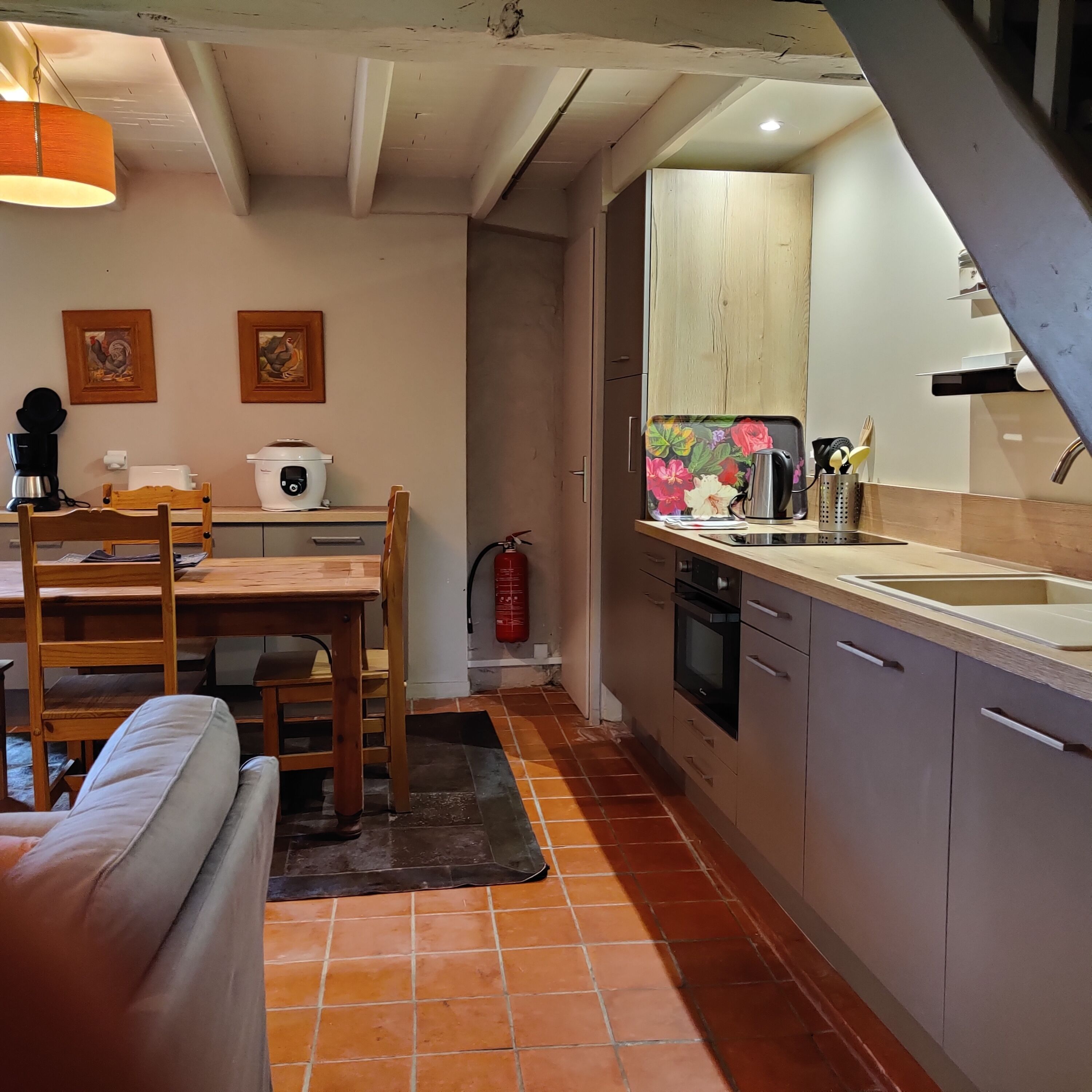 Een compact keuken met een eethoek, met onder meer een koffiezetapparaat, broodrooster en brandblusser.