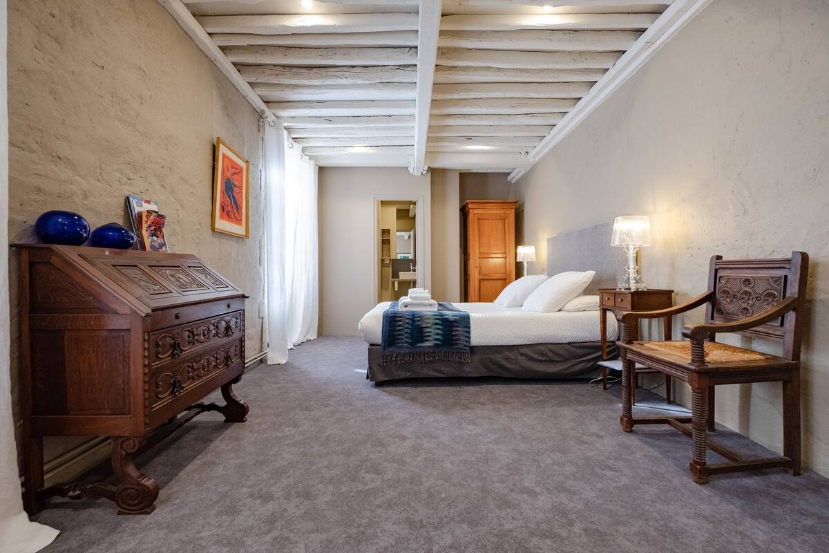 A bedroom with a bed, wooden dresser, and a chair.