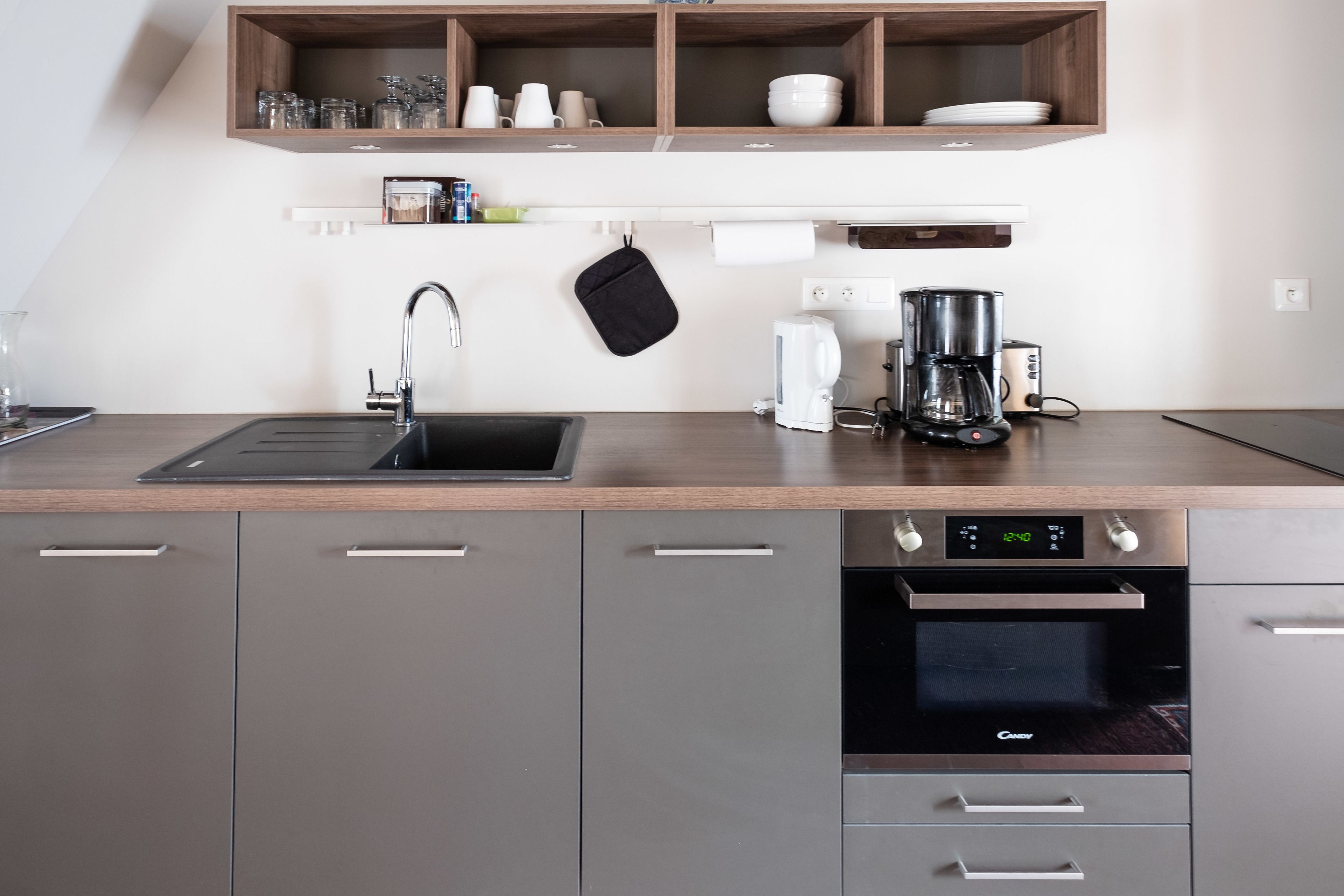A modern kitchen with a stainless steel sink, a coffee maker, and a built-in oven.