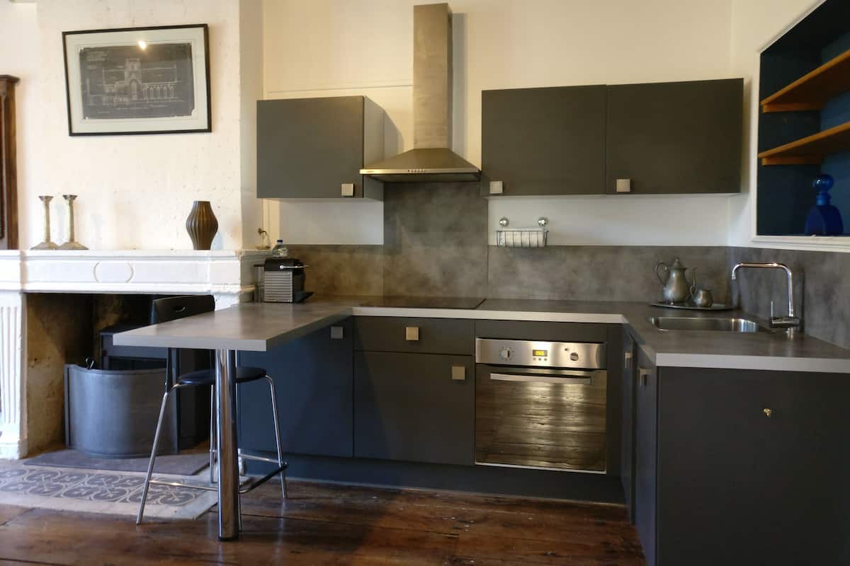 A modern kitchen with a central island, built-in oven, and stainless steel appliances.