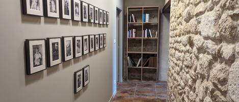 A hallway with framed photographs on the wall and a bookshelf with books.