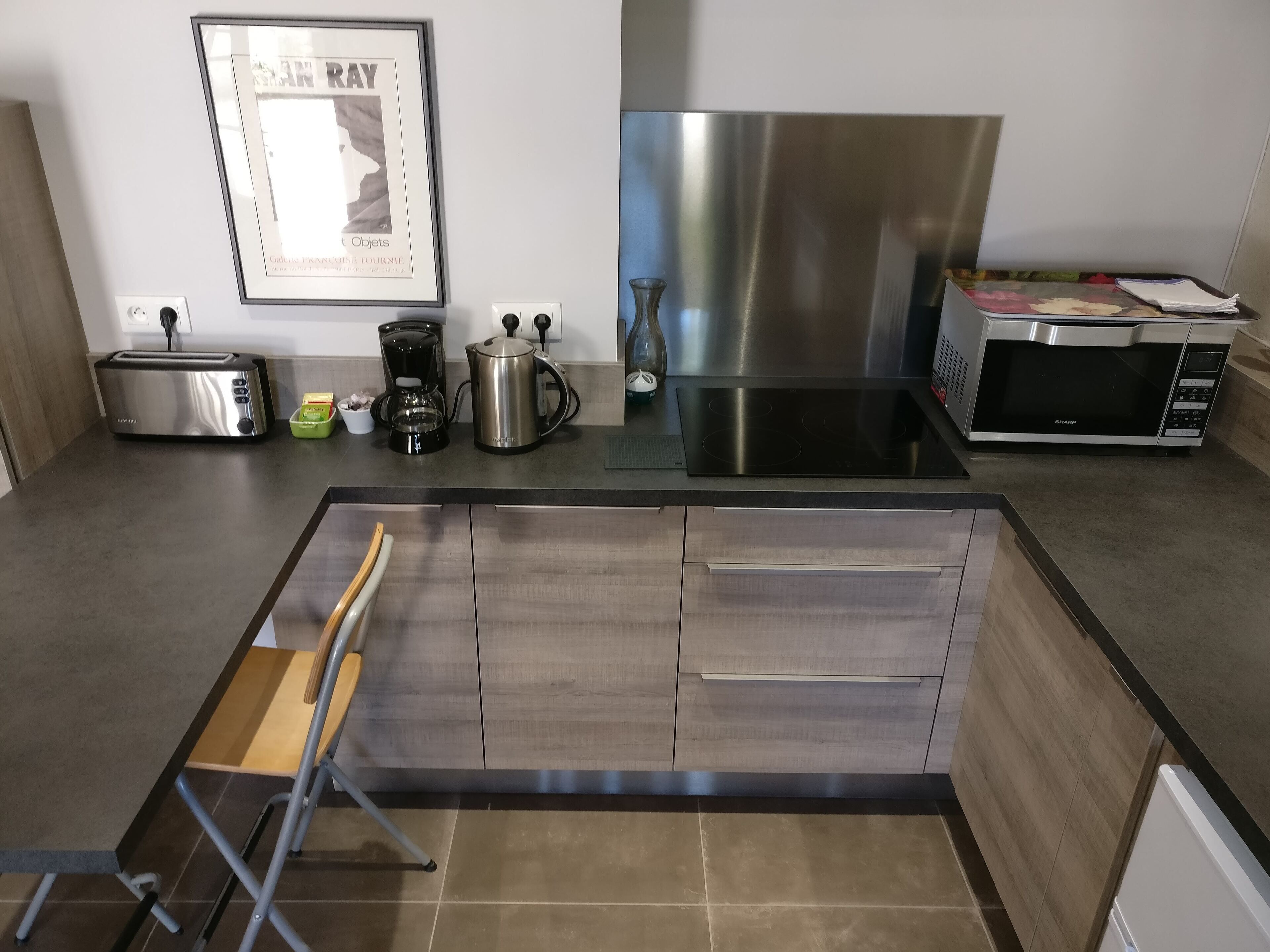 Una cocina moderna con campana extractora de acero inoxidable, tostadora, cafetera y microondas.