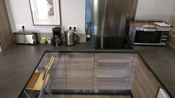 Una cocina moderna con campana extractora de acero inoxidable, tostadora, cafetera y microondas.