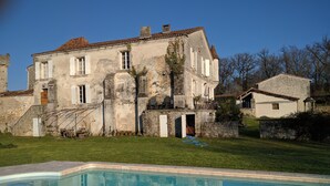 Un edificio grande y antiguo de piedra con una piscina delantera.