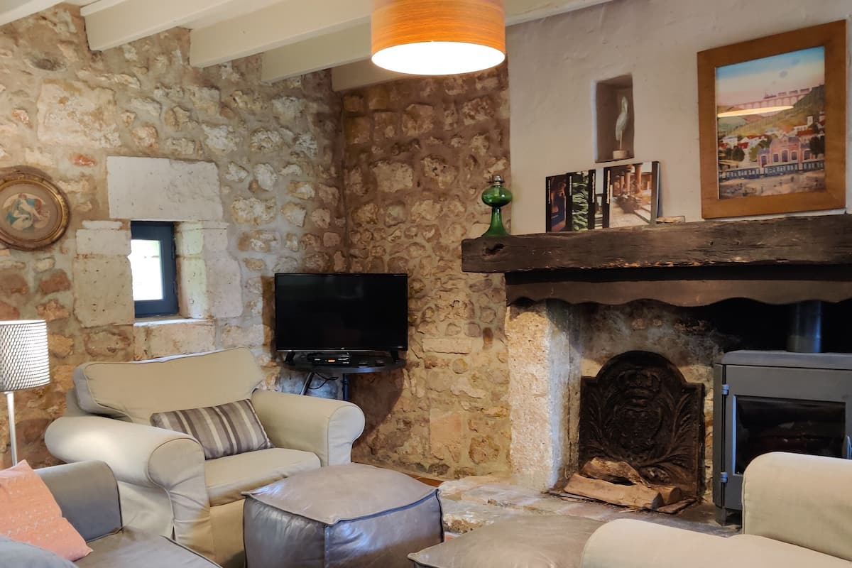 A living room with a stone wall, a fireplace, a television, and a sofa.