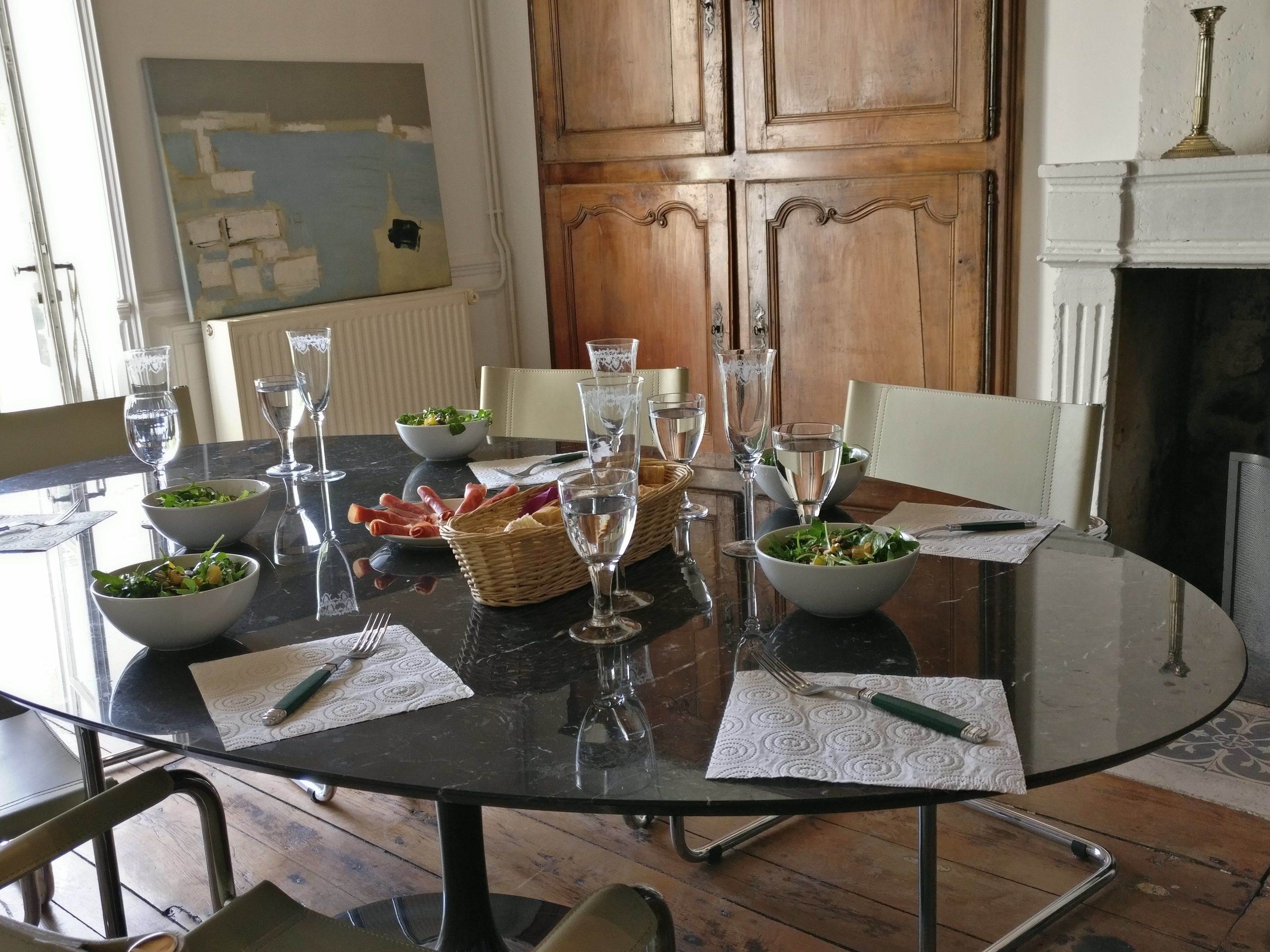Una mesa de comedor dispuesta con cristalería, ensaladas en boles y una cesta de pan.