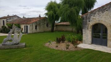 Un patio con edificios de piedra, una escultura y un césped bien cuidado.