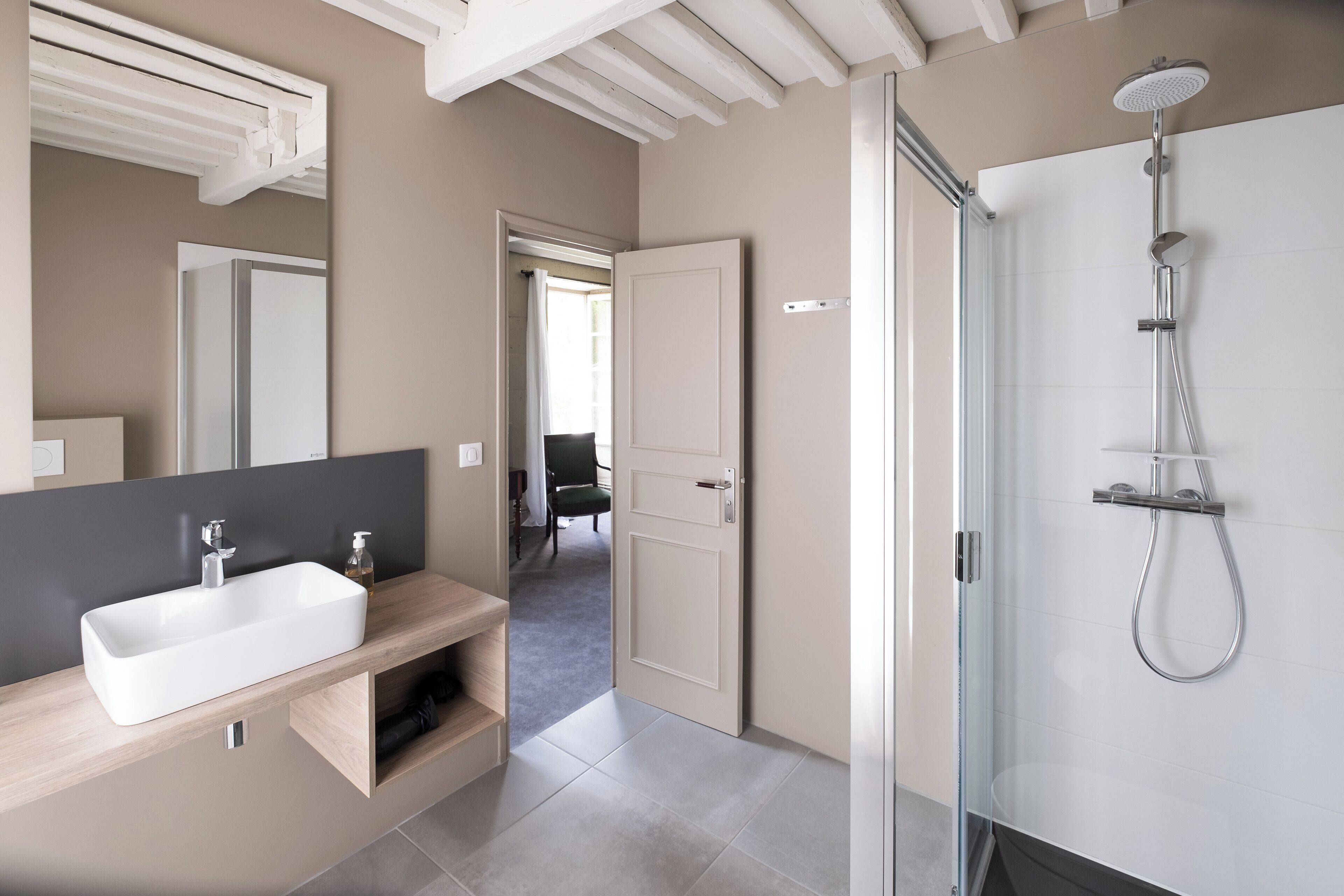 A modern bathroom with a large mirror, a rectangular sink, and a glass-enclosed shower area.