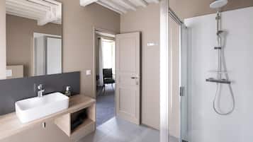 A modern bathroom with a large mirror, a rectangular sink, and a glass-enclosed shower area.