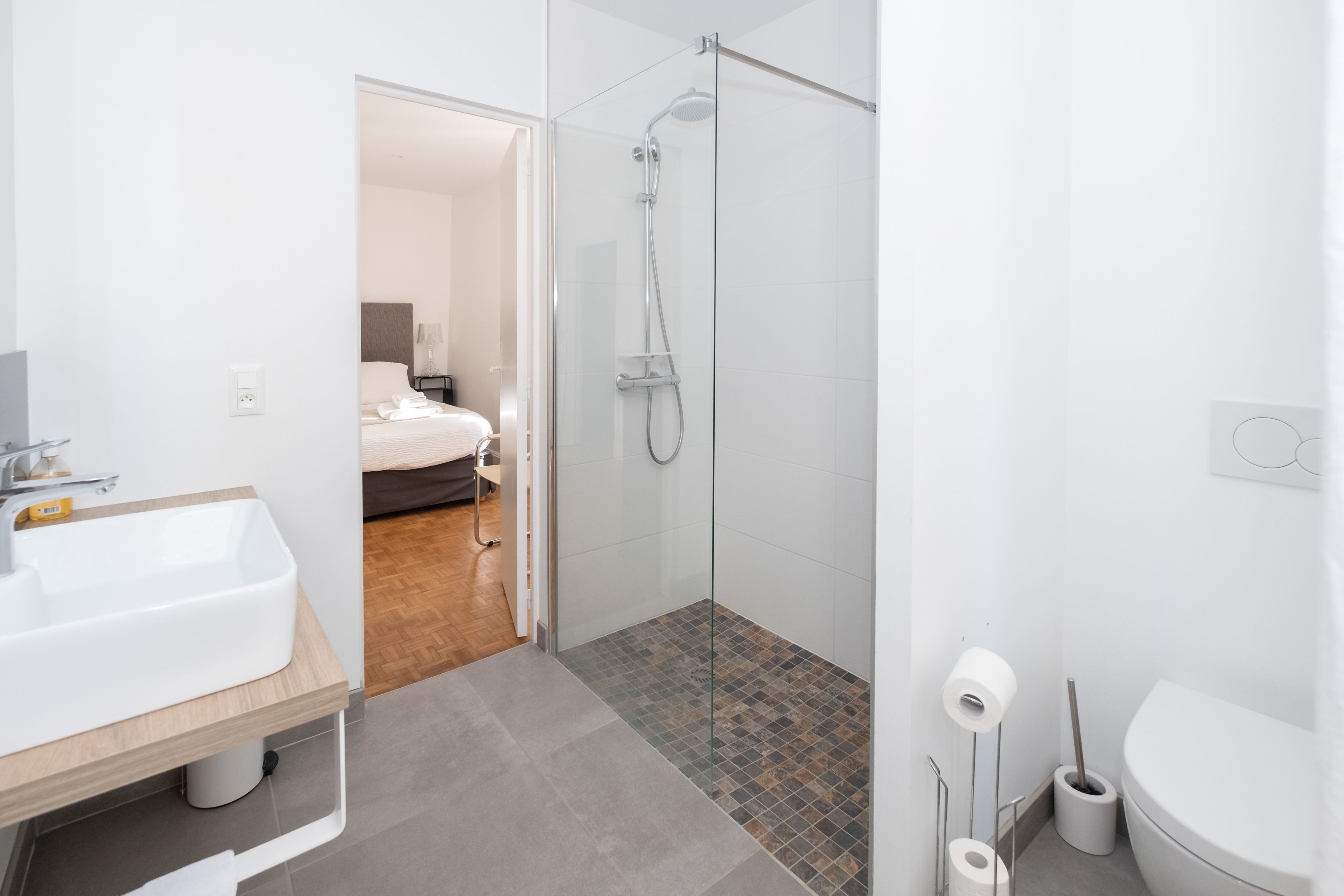 A modern bathroom with a glass-enclosed shower, a white sink, and a toilet.